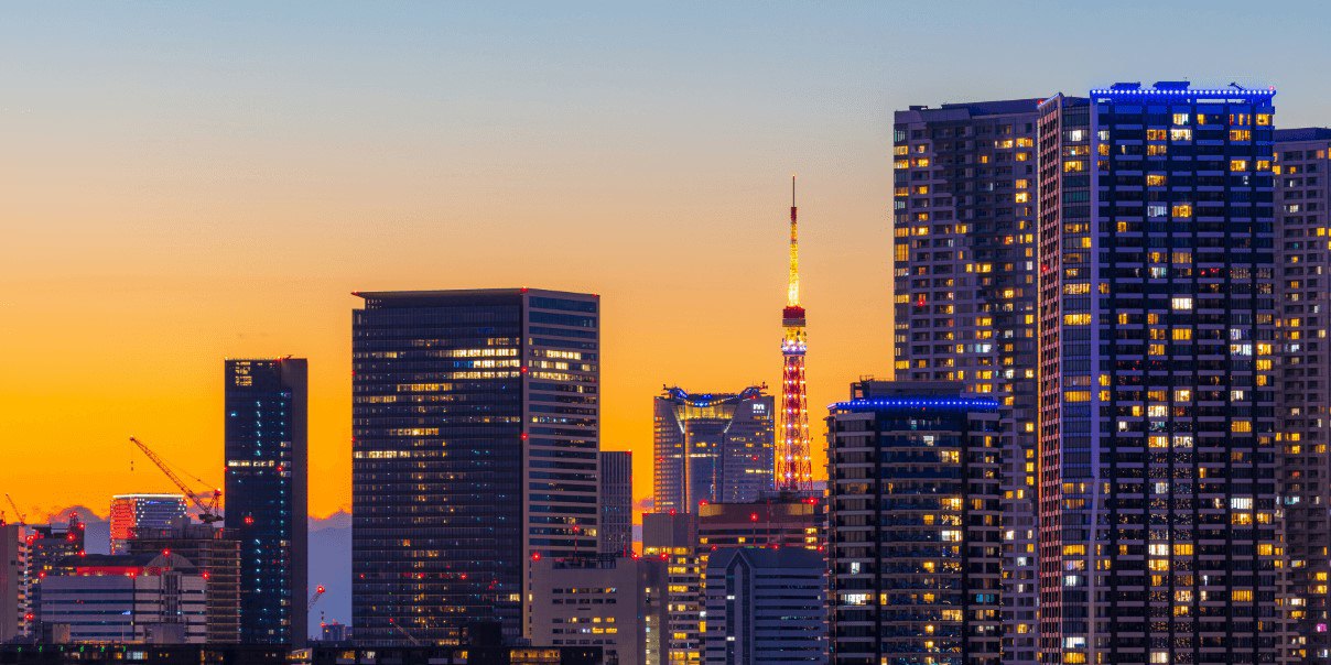 Cityscape at dusk with tall buildings and Tokyo Tower illuminated against an orange-blue sky