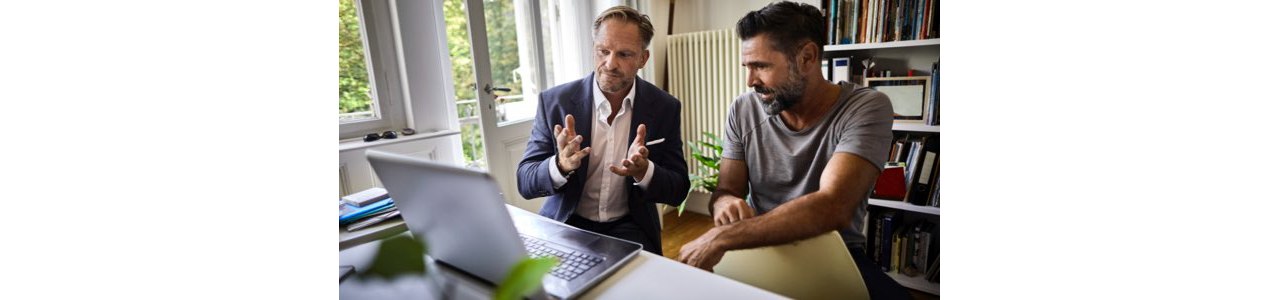 At home Financial Advice consultation. Two men looking at a laptop. The Adviser is explaining details to the client