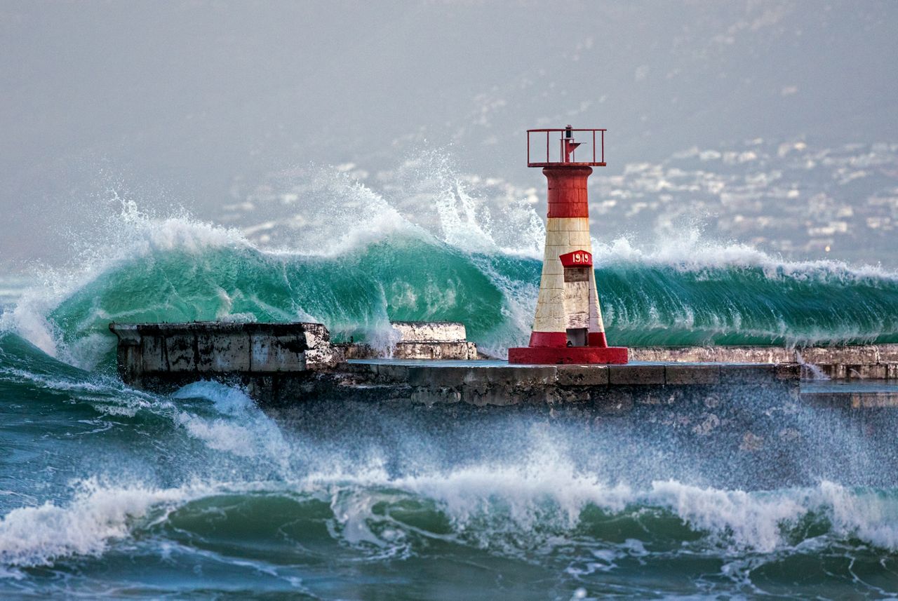 Big wave during winter swells crashing onto the harbor wall at Kalk Bay harbor in Cape Town, South Africa