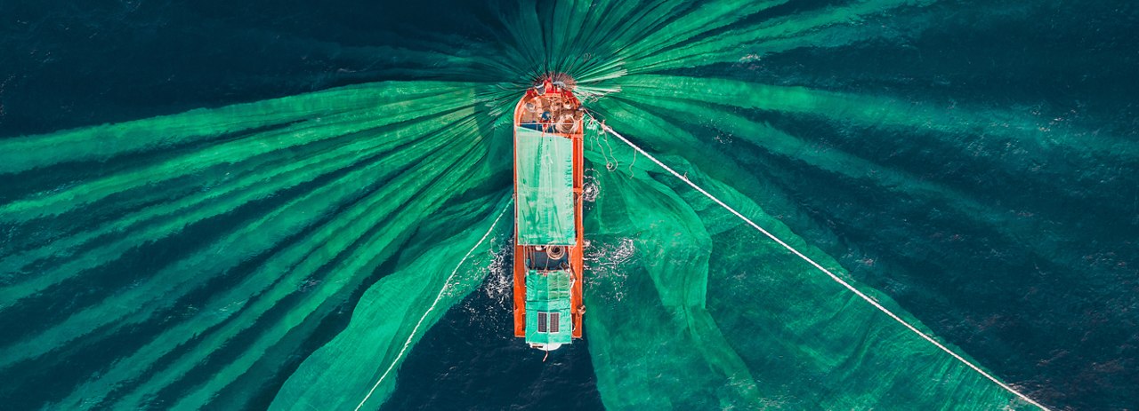 Aerial view of a boat surrounded by green fishing nets in the ocean.