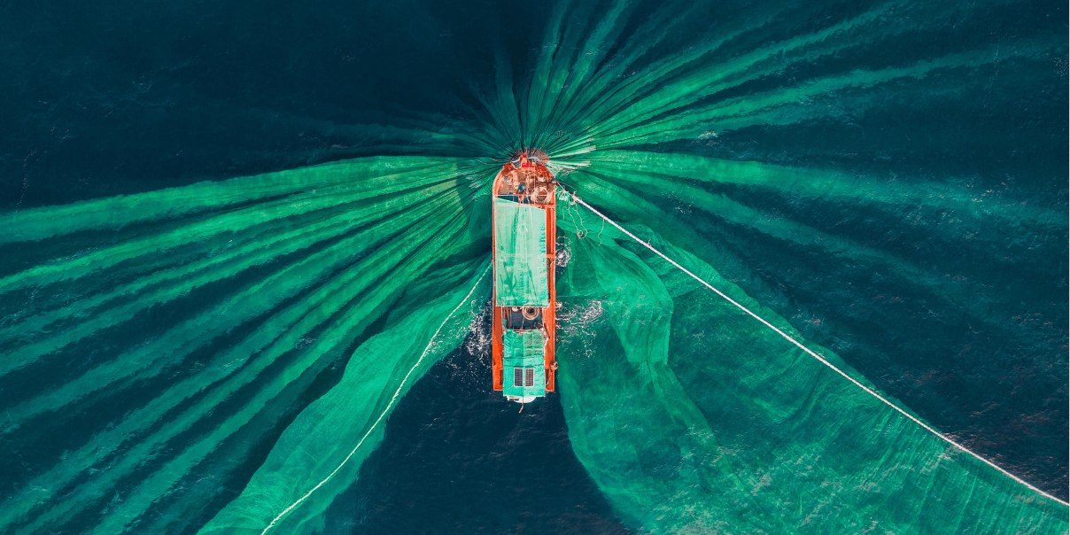Aerial view of a boat surrounded by green fishing nets in the ocean.