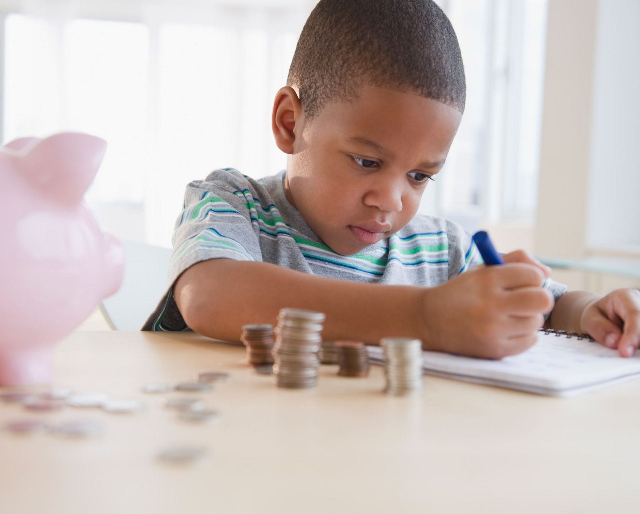 boy sitting on chair with piggy bank