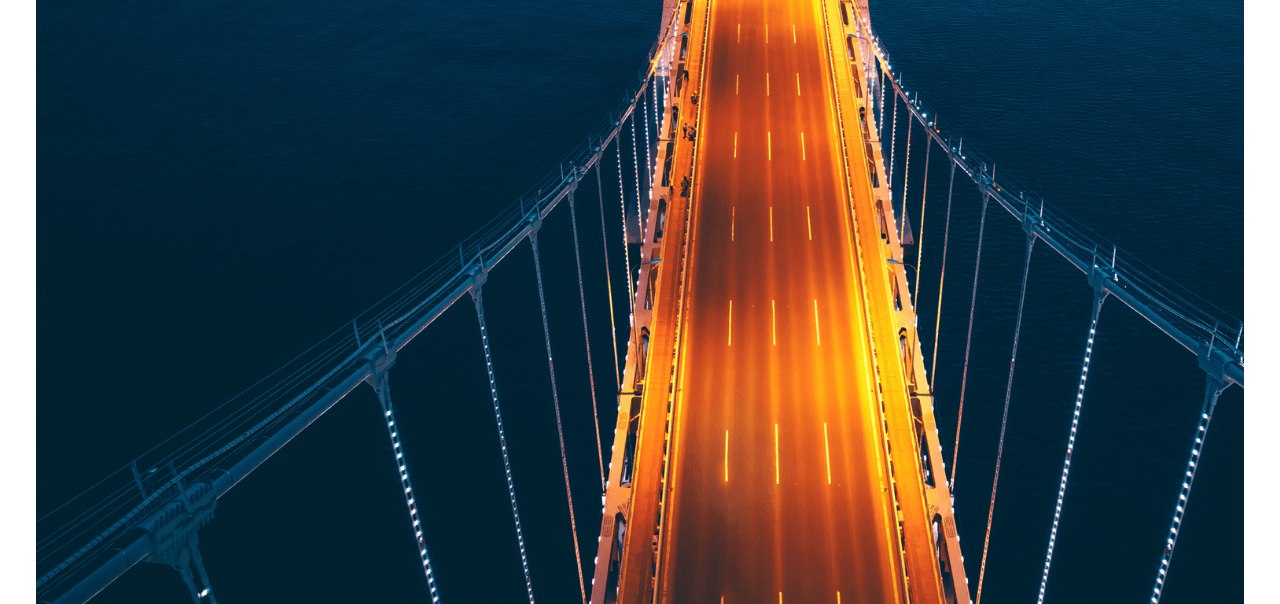 Bridge lit up at night over a river