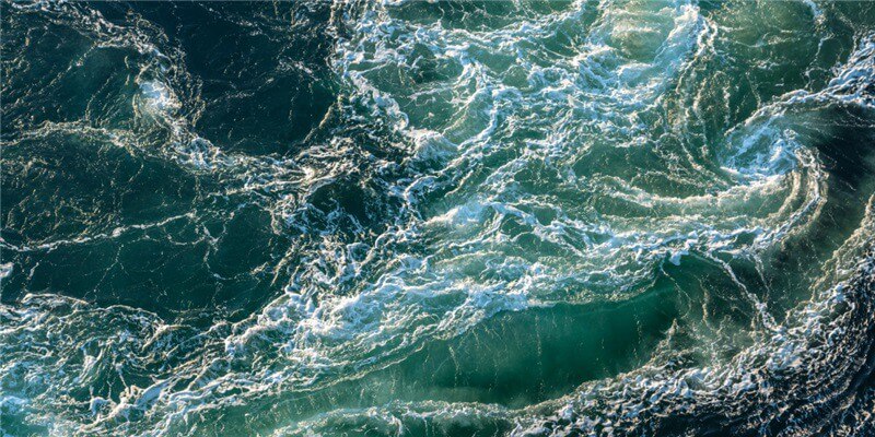 Churning ocean waves with swirling currents and foamy whitecaps