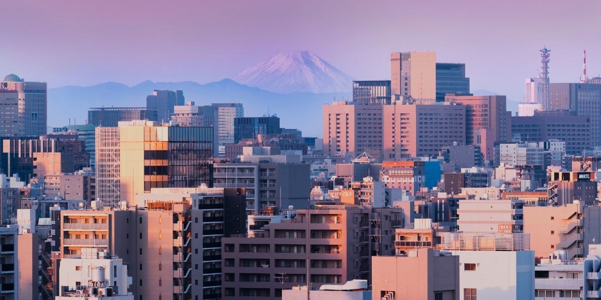 Cityscape at sunrise with Mount Fuji in the background.