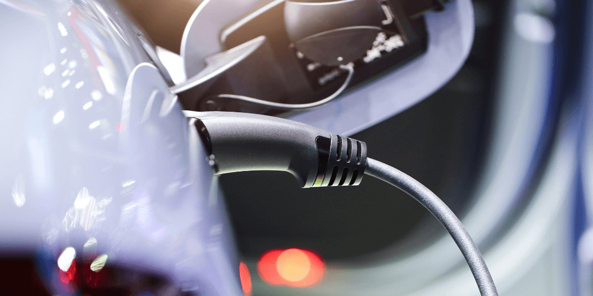 Close-up of an electric vehicle charging plug connected to a car