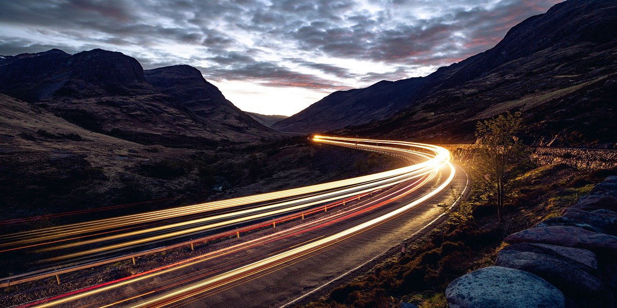 Light trails in the night on a remote road in mountains, Highlands, Scotland, UK.