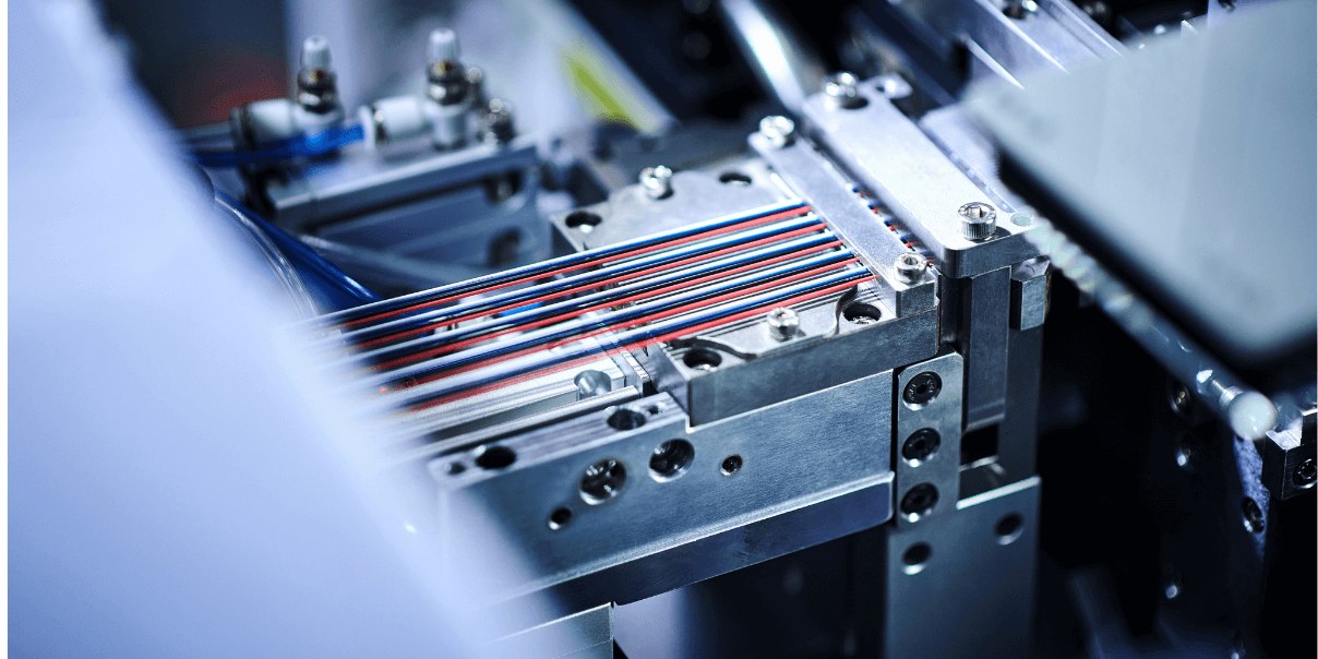 Close-up of industrial machinery with multiple colored wires aligned in a metal fixture