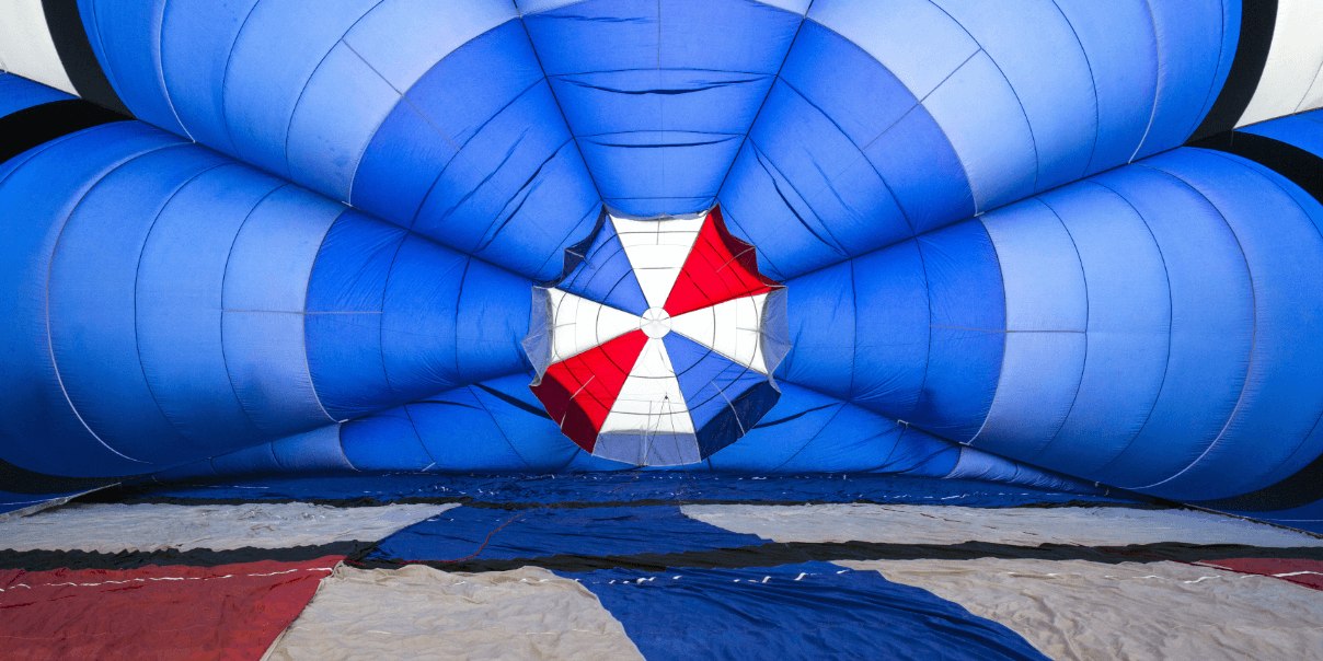 Inside view of a blue hot air balloon with a red and white center, showcasing the colorful, inflated fabric structure.