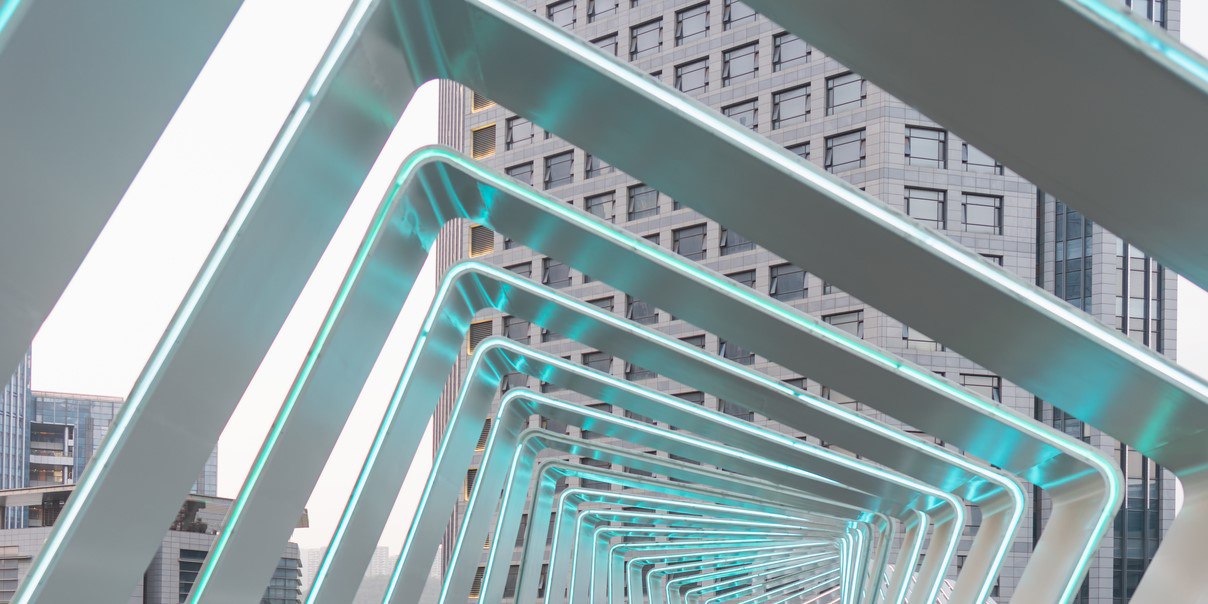 A metal bridge with illuminated lights in front of a tall building