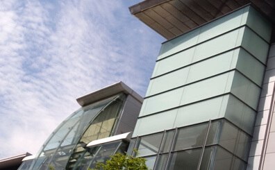 A modern building featuring glass windows, set against a clear blue sky, showcasing contemporary architecture.