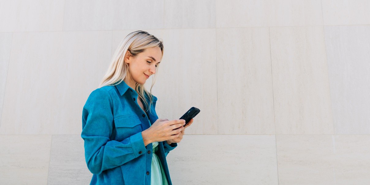 Woman uses a phone next to a concrete wall