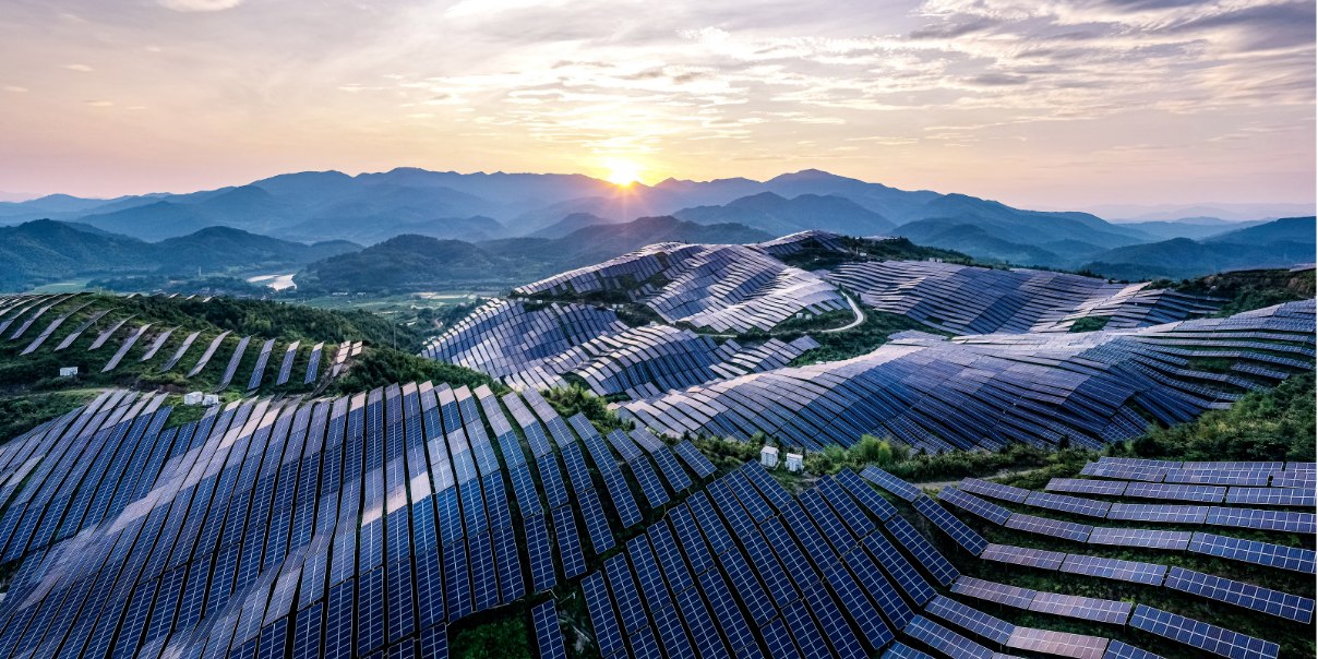  a solar farm stretching across hilly terrain, with rows of solar panels aligned to capture sunlight.