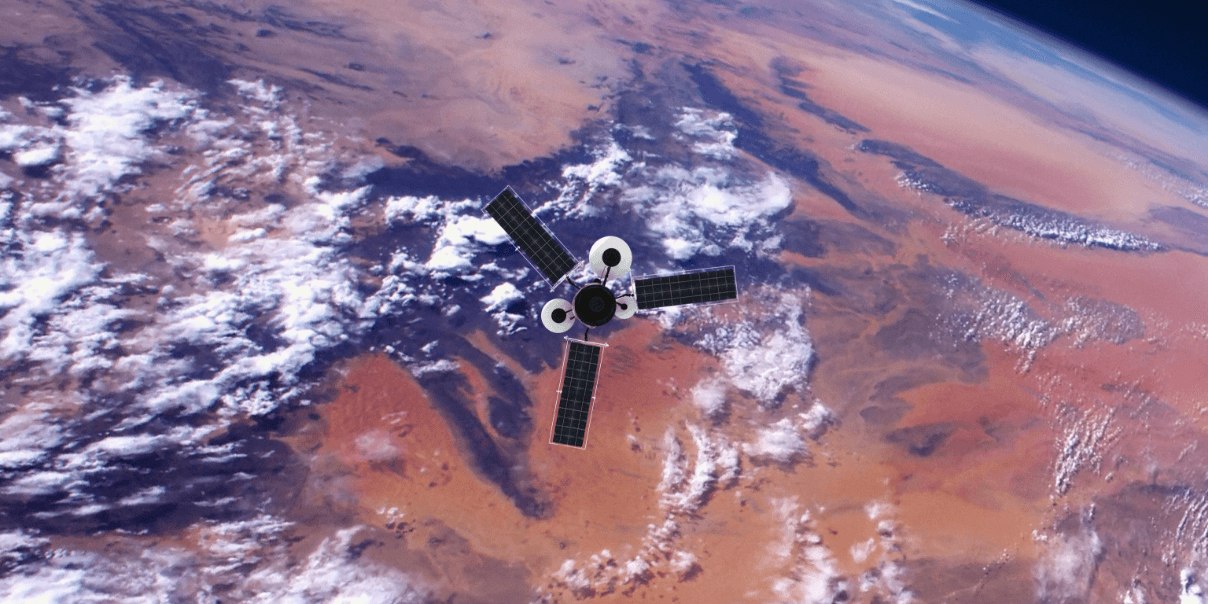 A satellite with solar panels orbits above Earth, capturing an aerial view of a desert landscape with scattered clouds.