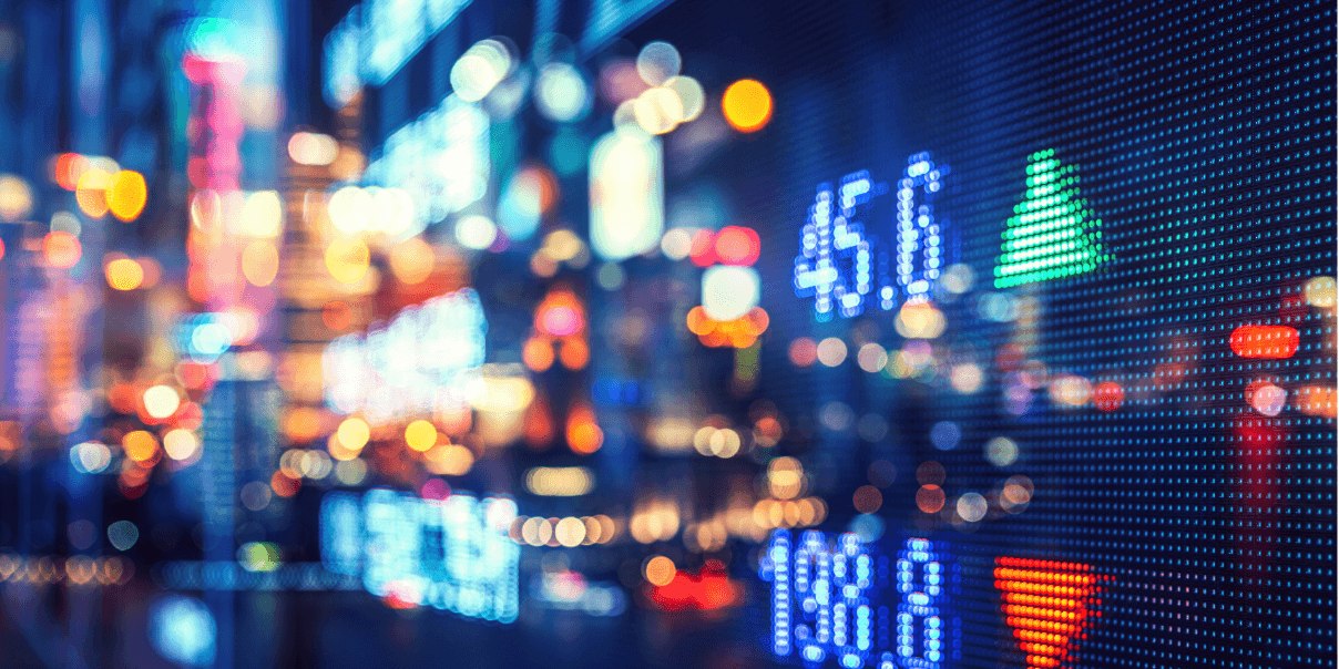 The blurred city lights add a sense of motion and energy, reflecting the fast-paced nature of both city life and financial trading.