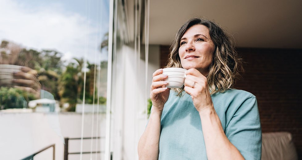Contemplative mature woman looking throught the window at home