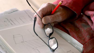 person keeping his hand on the paper holding the glasses and a pencil