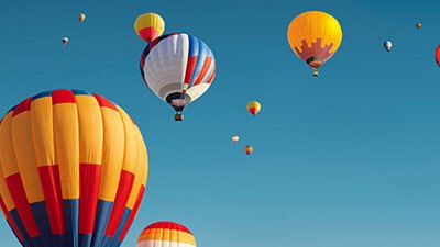 A collection of bright and colorful hot air balloons floating gracefully in the sky, showcasing a lively and cheerful scene.