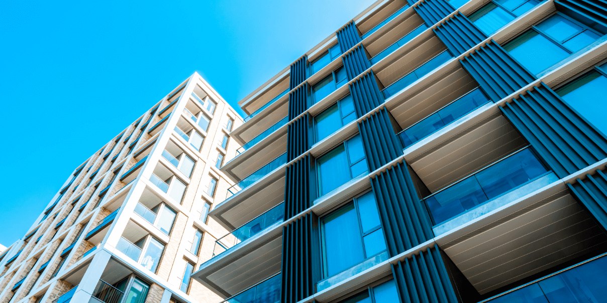 Two contrasting apartment buildings viewed from below against a clear blue sky