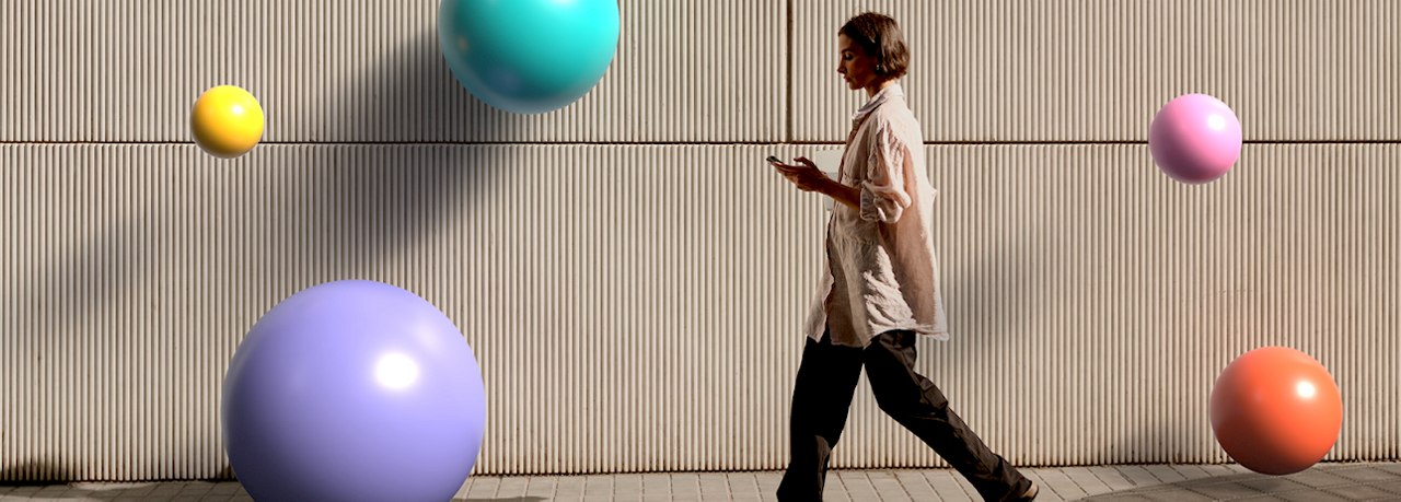 a person walking in front of a ribbed wall, engaged with their smartphone.
