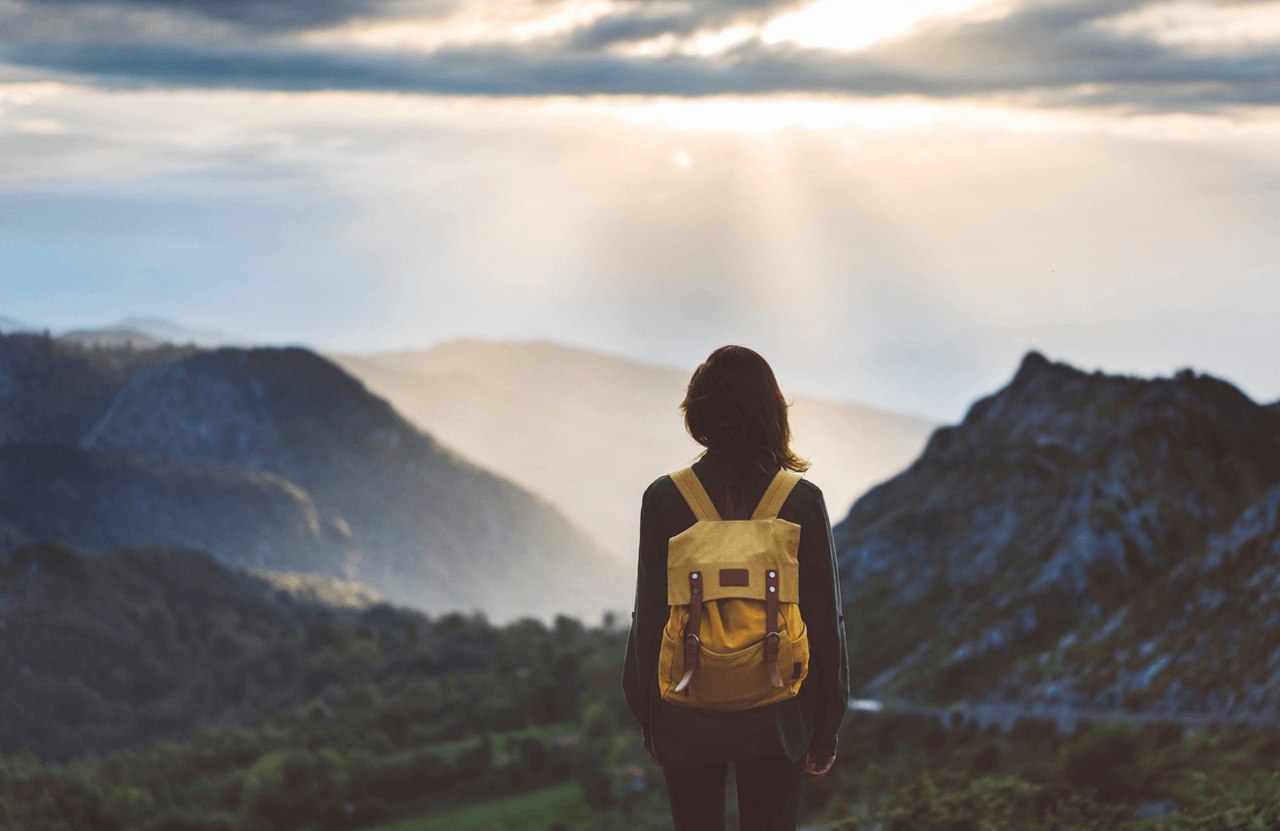 woman starring at the mountains with a cloudy sky